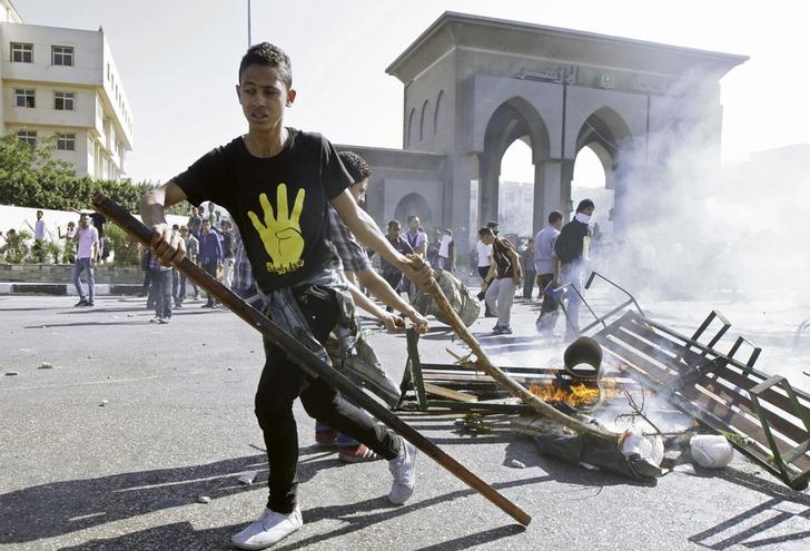 Student sets fire to sticks during clashes with riot police in front of the main offices of Al-Azhar University in Cairo